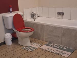 a bathroom with a toilet with a red seat and a bath tub at Private Guest suite in Ferndale in Johannesburg