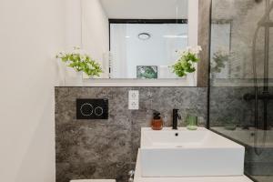 a bathroom with a white sink and a mirror at Design-Studio mit Balkon - Nähe Donau in Passau +4 photos