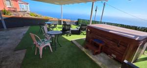 a patio with chairs and tables and an umbrella at Refúgio com jacuzzi e vista mar in Estreito da Calheta