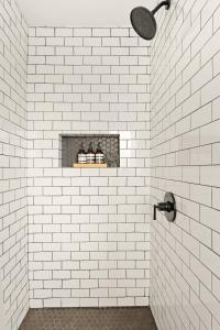 a white tiled bathroom with a shelf with bottles at 3BR 2Bth, 10 min 2 JTNP, Zen Garden,Hot Tub,EV Chg in Joshua Tree +36 photos