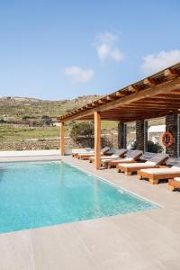 a swimming pool with benches and a pergola at Hillside Collection - by Hospirit in Mikonos