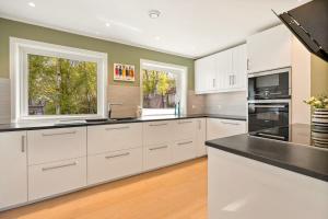 a kitchen with white cabinets and two windows at Lykkebo in Stavanger