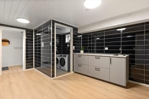 a bathroom with black tiled walls and a washing machine at Lykkebo in Stavanger +33 photos