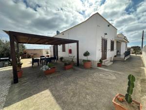 a white building with a table and potted plants at Villa Maria in Campobello di Mazara