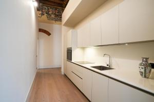 a kitchen with white cabinets and a wooden floor at Palazzo Zoya - Elegant Historic Suites - Asti Center - Near Langhe & Monferrato in Asti