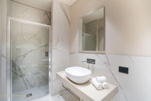 a white bathroom with a sink and a shower at Palazzo Zoya - Elegant Historic Suites - Asti Center - Near Langhe & Monferrato in Asti