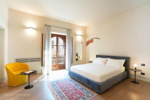 a bedroom with a bed and a chair and a window at Palazzo Zoya - Elegant Historic Suites - Asti Center - Near Langhe & Monferrato in Asti