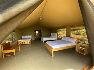 a room with two beds and a table in a tent at Nature Lovers Camp in Sekenani