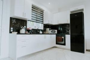 a kitchen with white cabinets and a black refrigerator at Nafos Villa Stella in Levkákia