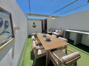 eine Terrasse mit einem Holztisch und einigen Stühlen in der Unterkunft VILA TABARCA QUALITY & LUXURY in Tabarca