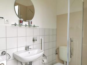 a bathroom with a sink and a toilet and a mirror at Ferienwohnung 1 Nordsee Gulfhof Dornum - mit großem Garten in Roggenstede +46 photos
