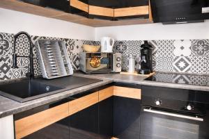 a kitchen with black and white tiles on the wall at Le 5 Place Carnot in Douai