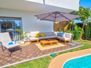 a patio with a couch and an umbrella next to a pool at Villa Serena in Mijas Costa