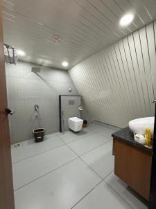 a white bathroom with a toilet and a sink at Neora Farms in Simrol