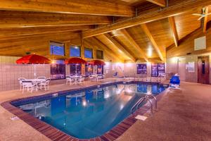 a swimming pool with tables and chairs in a building at AmericInn by Wyndham Okoboji in Okoboji