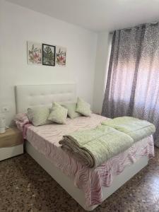 a bedroom with a bed with pink and green pillows at Apartamento Dúplex vacacional in Burriana