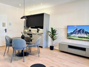 a living room with a dining table and a flat screen tv at Schwanstein Apartments Füssen ZENTRUM in Füssen