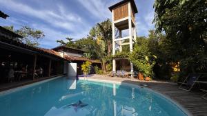 a swimming pool in front of a house with a building at Pousada Tiê Sahy in Barra do Sahy