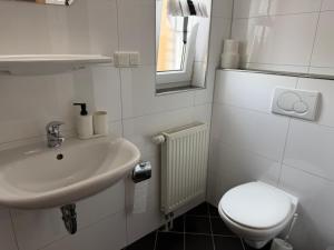 a white bathroom with a toilet and a sink at Pension Rialto in Staufenberg +16 photos