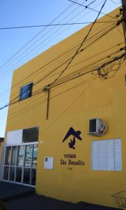 a yellow building with a sign on the side of it at Pousada São Benedito CP in Cachoeira Paulista