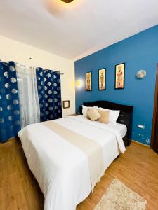 a bedroom with a large white bed with blue walls at Kalon Elpis Villa in Ooty +9 photos