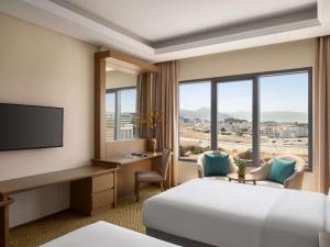 a hotel room with a bed and a desk and window at Mercure Muscat in Muscat