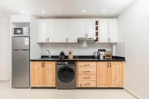 a kitchen with white cabinets and a dishwasher at Taghazout Bay Chic Residence Sea View in Tamraght Ouzdar