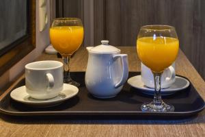 a tray with two glasses of orange juice and two cups at Elia Deluxe Accommodation in Kalabaka +30 photos