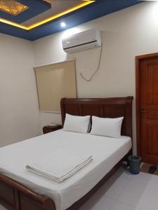 a bedroom with a bed with a air conditioner on the wall at Nursery Suites in Karachi +8 photos