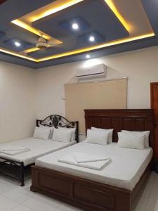two beds in a room with a ceiling at Nursery Suites in Karachi