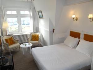 a bedroom with a bed and two chairs and a table at La Villa L'Argentine in Cabourg