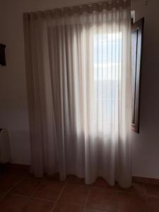 a white curtain in a room with a window at La Dimora del Molo in Fuscaldo