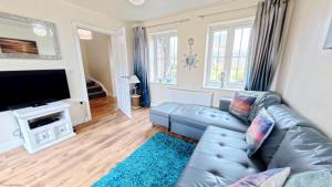 a living room with a blue leather couch and a flat screen tv at Sunset Cottage - Part of the The Bay Filey Holiday Village with pool, gym and direct beach access, pub, restaurant, tennis and meadows walks in Filey