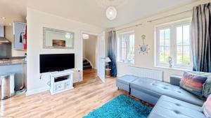 a living room with a blue couch and a flat screen tv at Sunset Cottage - Part of the The Bay Filey Holiday Village with pool, gym and direct beach access, pub, restaurant, tennis and meadows walks in Filey
