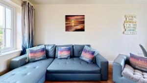 a blue couch in a living room with pillows at Sunset Cottage - Part of the The Bay Filey Holiday Village with pool, gym and direct beach access, pub, restaurant, tennis and meadows walks in Filey