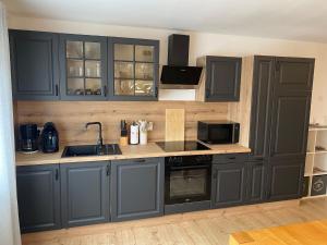 a kitchen with gray cabinets and a sink and stove at Ferienwohnung Rickelhoff in Olpe