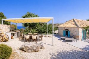a table and chairs under a yellow canopy in front of a house at Light & Stone Villa, Kefalonia in Lixouri