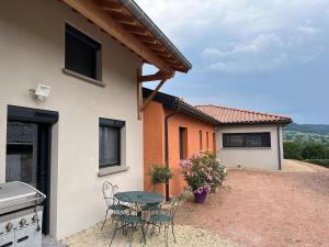a patio with a table and chairs in front of a house at L'Escapade Bourguignonne, à 10 minutes de Cluny, petit déjeuner inclus! in Clermain
