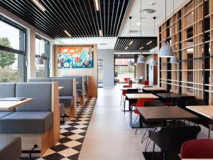 a dining room with tables and chairs and windows at ibis Hotel Berlin Airport in Berlin