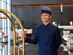 a young man in blue uniform holding a gold door at Grand Mercure Batam Centre in Batam Center +116 photos