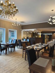 a restaurant with wooden tables and chairs and a chandelier at Hotel Haus Hubertus in Schneverdingen