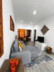 a living room with a gray couch and a tv at Casa Galante in Furnas