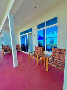 a room with two chairs and a table and windows at Karibu House Paje in Paje