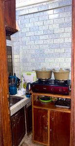 a kitchen with a stove and a brick wall at Studio meublé akwa in Douala +13 photos