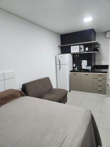 a bedroom with a bed and a chair and a kitchen at West Fit Padrão 05 in Mossoró