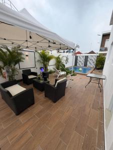 a patio with chairs and tables and a white canopy at Oasis in San Isidro