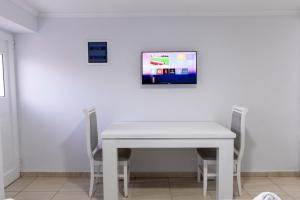 a white table and chairs with a tv on a wall at Villa Kevin's in Sarandë