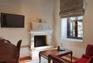 a living room with a fireplace and a tv at Αρχοντικό Ταξίμι - Ανθέων Έμπνευση in Argalasti