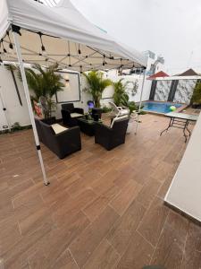 a patio with a white tent and chairs and a pool at Oasis in San Isidro
