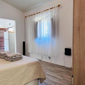 a bedroom with a bed and a window with white curtains at Vivenda Silva in Santo António da Charneca